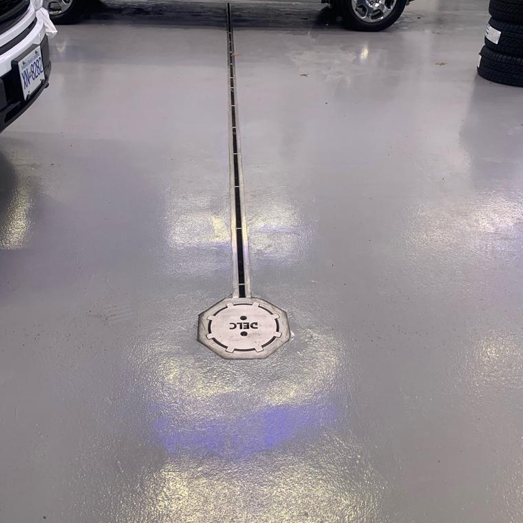 Stainless area drain and slot run in a coated floor with a vehicle parked over it