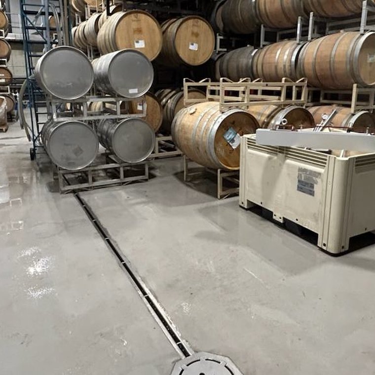 Stainless slot drain running along a brewery barrel storage floor