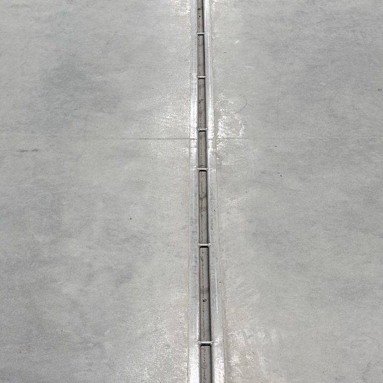 Stainless slot drain flush in a finished concrete corridor floor