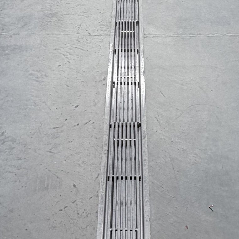 Stainless trench drain grate running down a plant corridor
