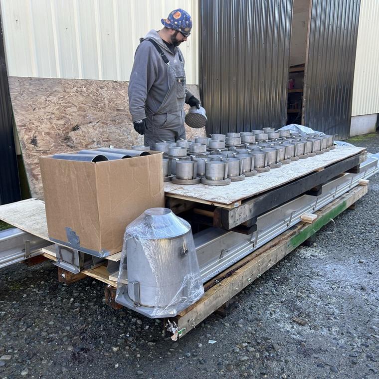 DELC staff member checking a pallet of stainless steel drain fittings before dispatch