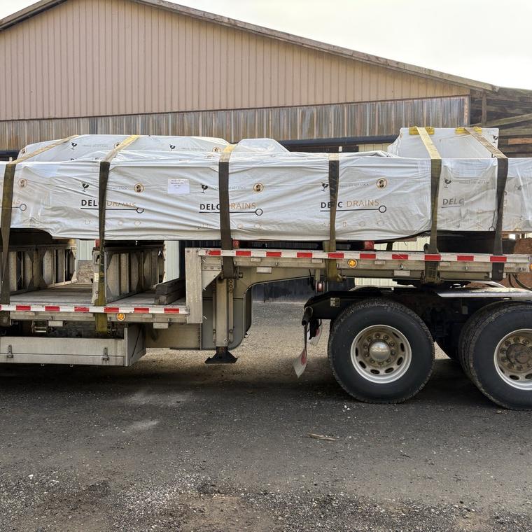 Wrapped stainless steel drain runs strapped to a flatbed truck for delivery