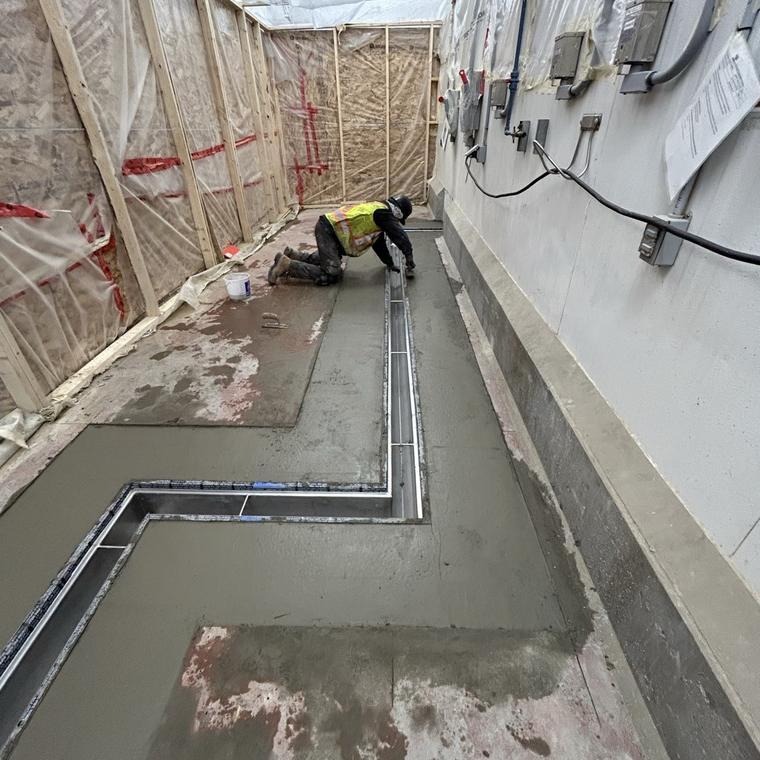 Perimeter and cross-floor stainless drain runs being installed during a plant fit-out