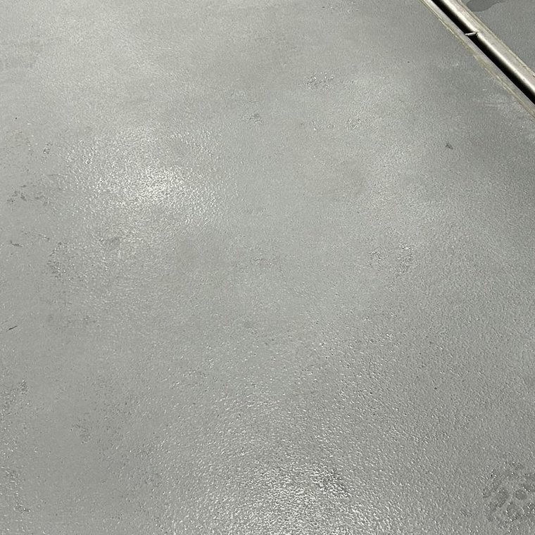 Close-up of a stainless slot drain finished flush with a coated processing floor