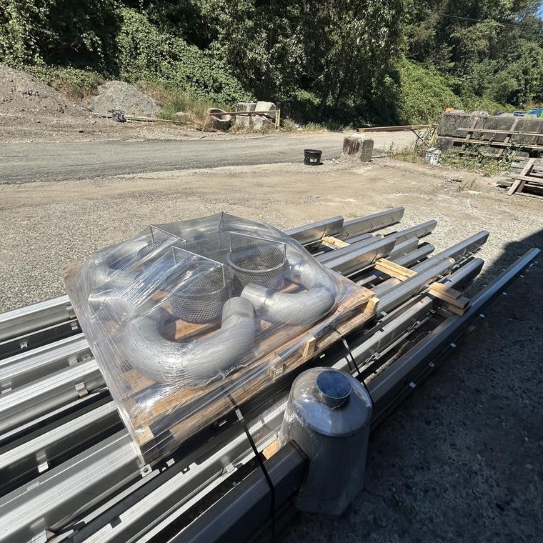 Stainless drain sections and wrapped P-traps staged outdoors on a job site