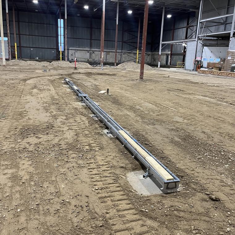 Long stainless trench drain run set on compacted subgrade inside a new building shell